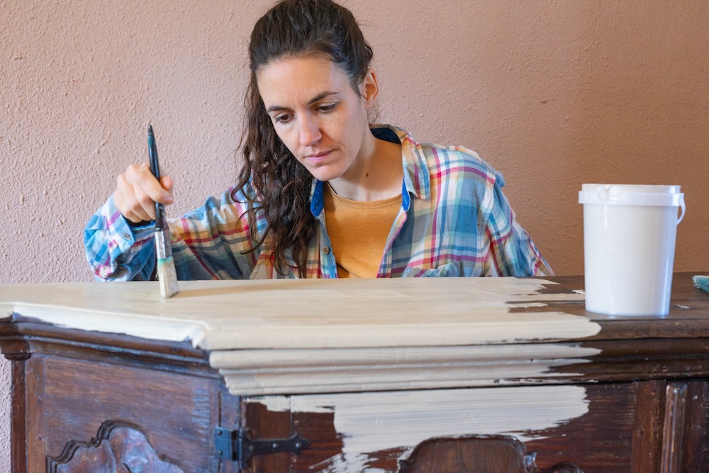 woman painting an old dresser