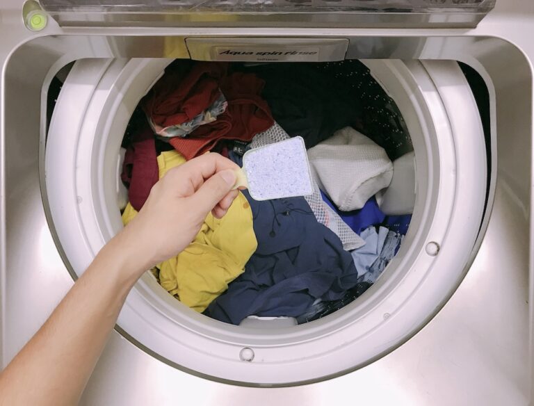 person loading laundry into machine and adding powdered detergent