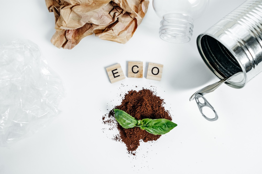 words spelling eco with plastic paper and tin on a table