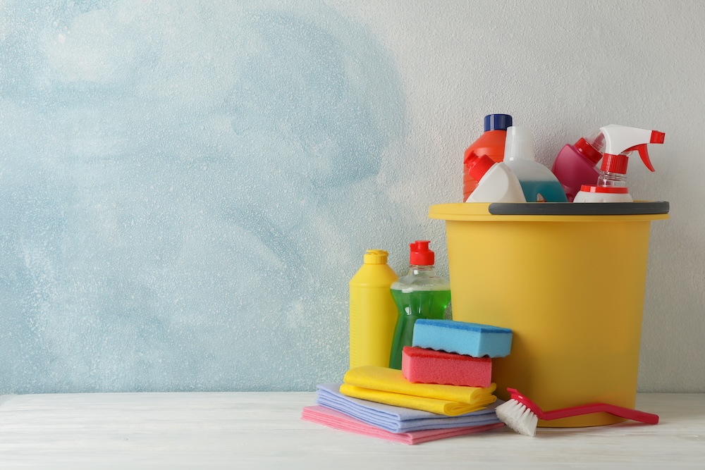 household cleaners in a bucket with sponges and supplies