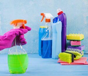 hand with cleaning glove spraying cleaning product