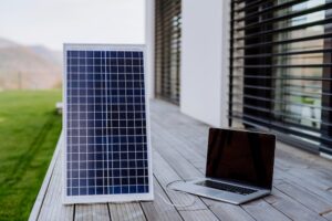 laptop plugged into a solar panel outside on the porch