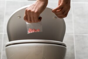 person flushing drugs down the toilet