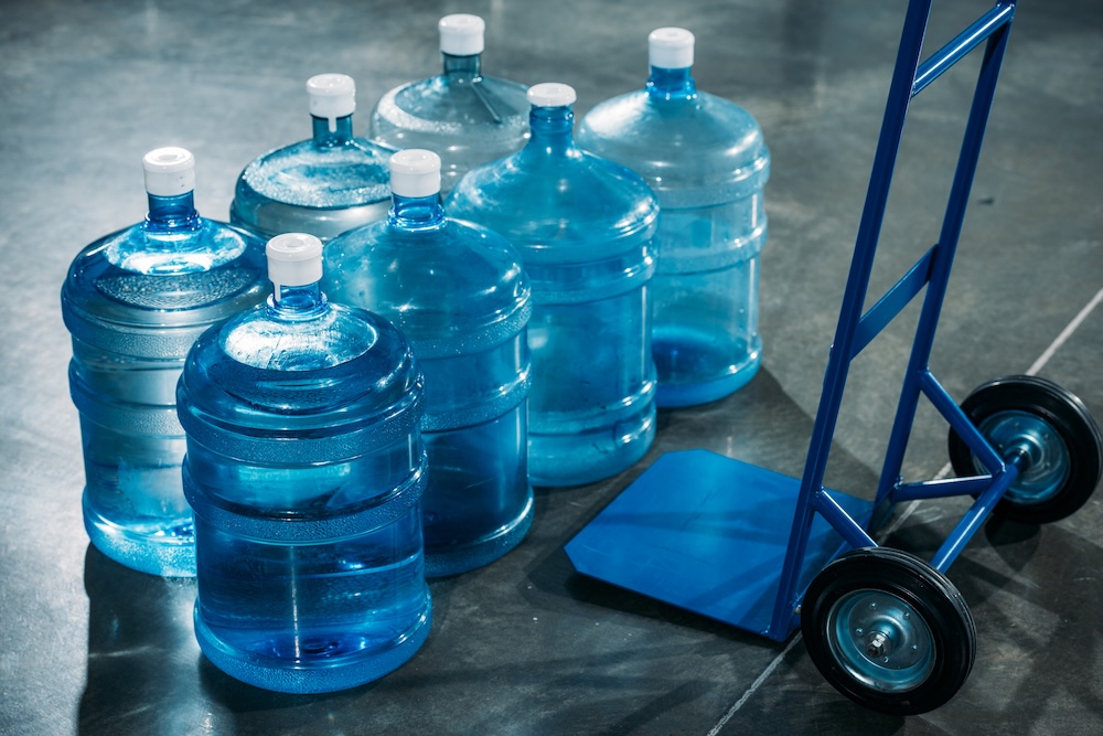 gallons of water in bottles next to a metal dolly