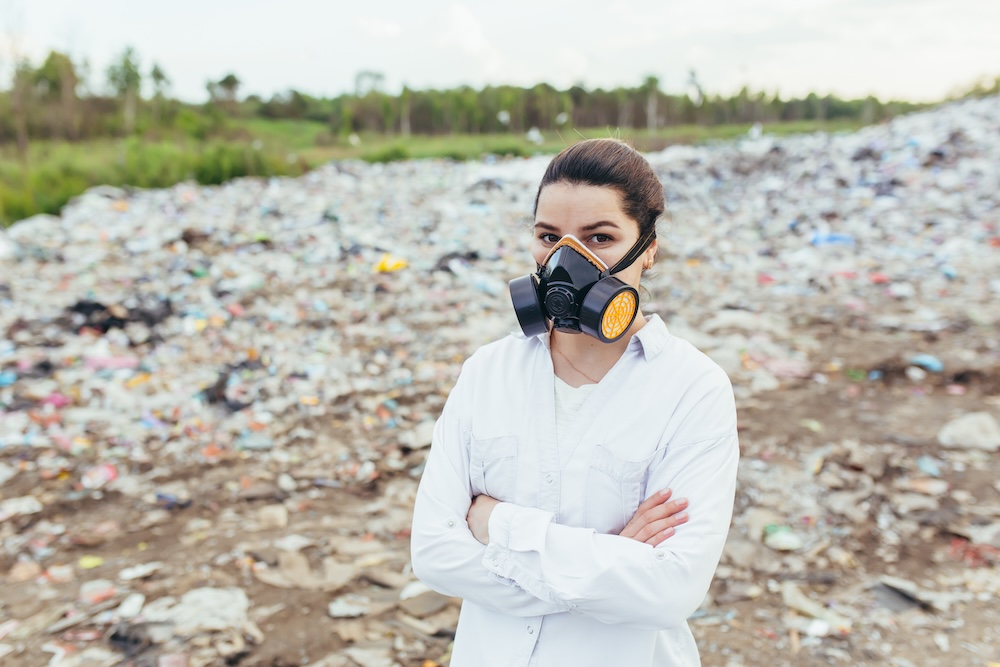 woman standing in land fill wearing a mask