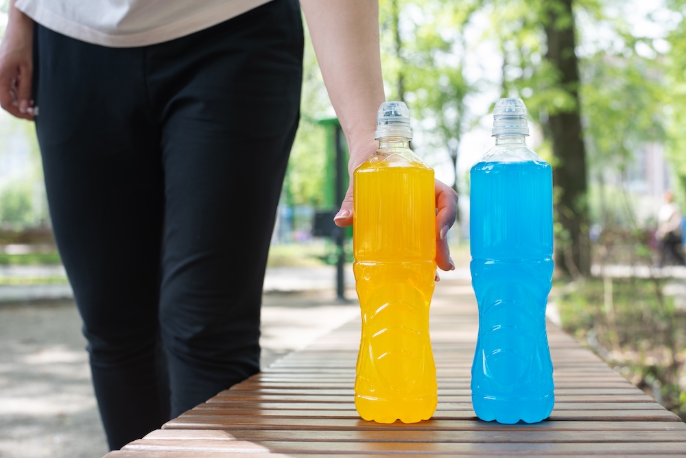two full bottles of orange and blue vitamin water on a bench