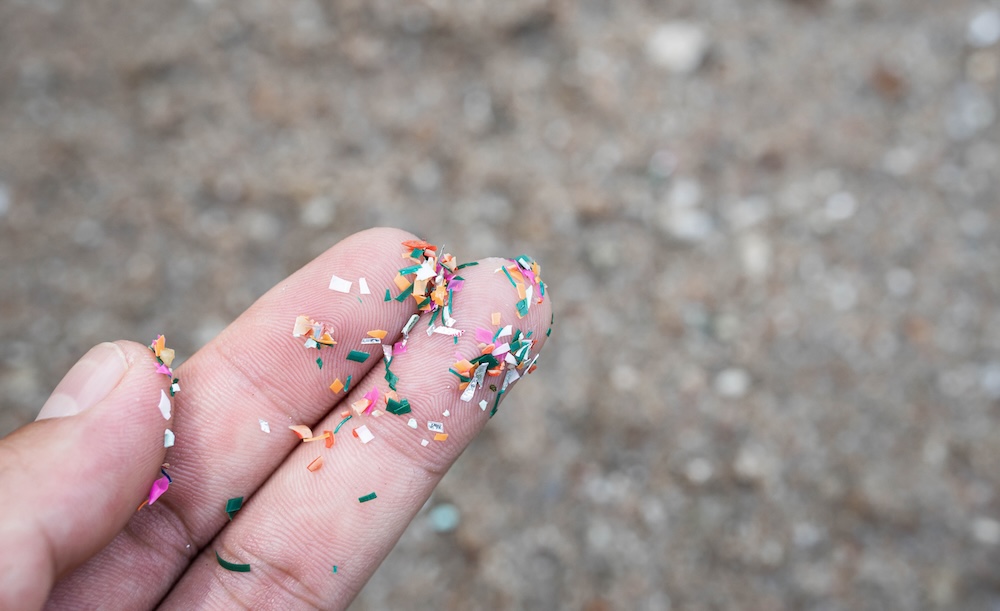 microplastics on fingertips of a person at the beach