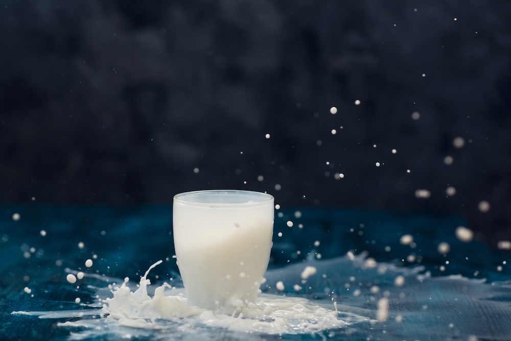 glass of milk sitting on a wet table with splashes