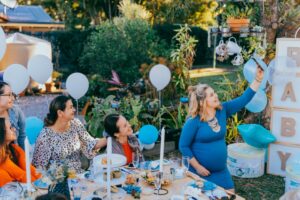 women sitting around a table for baby shower with lots of gifts