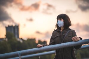 woman standing on a bridge with air pollution plant behind her