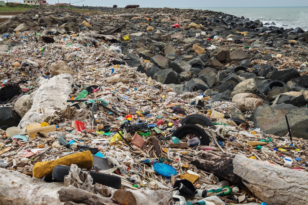 spilled garbage on rocks near beach shoreline