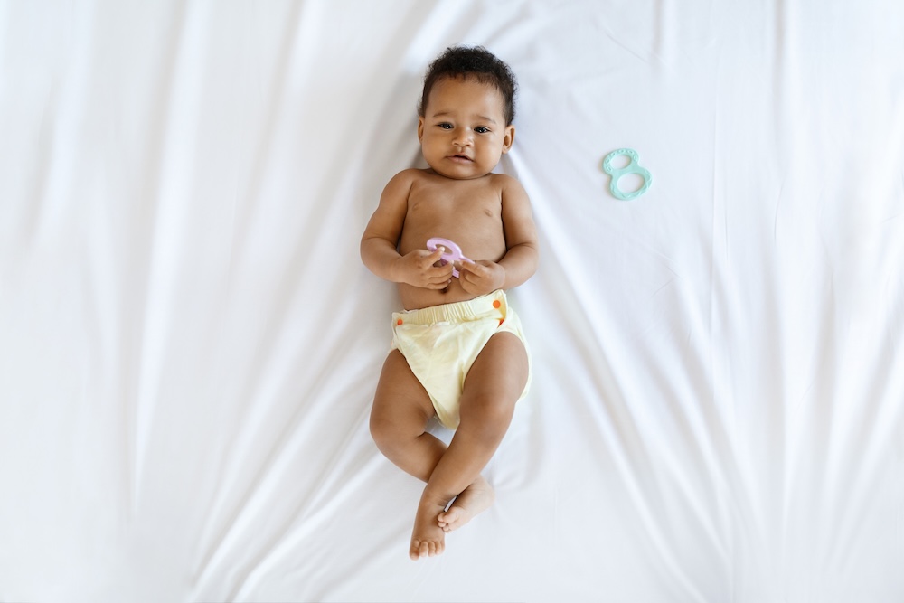 sweet baby laying on bed wearing reusable diaper