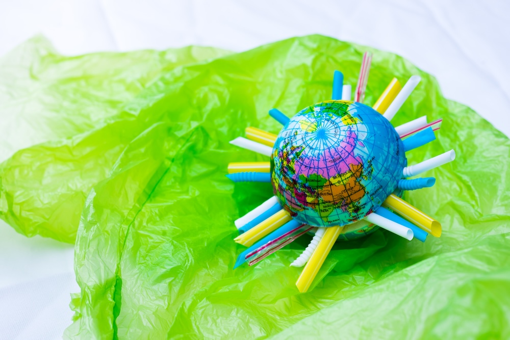 earth with straws sticking out of it on a plastic bag