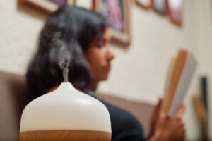 woman reading a book with aroma diffuser releasing VOCs into the air