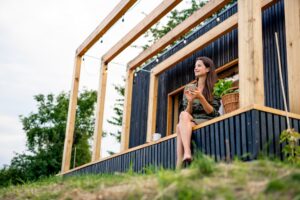 woman sitting outside her outdoor cabin that is off grid