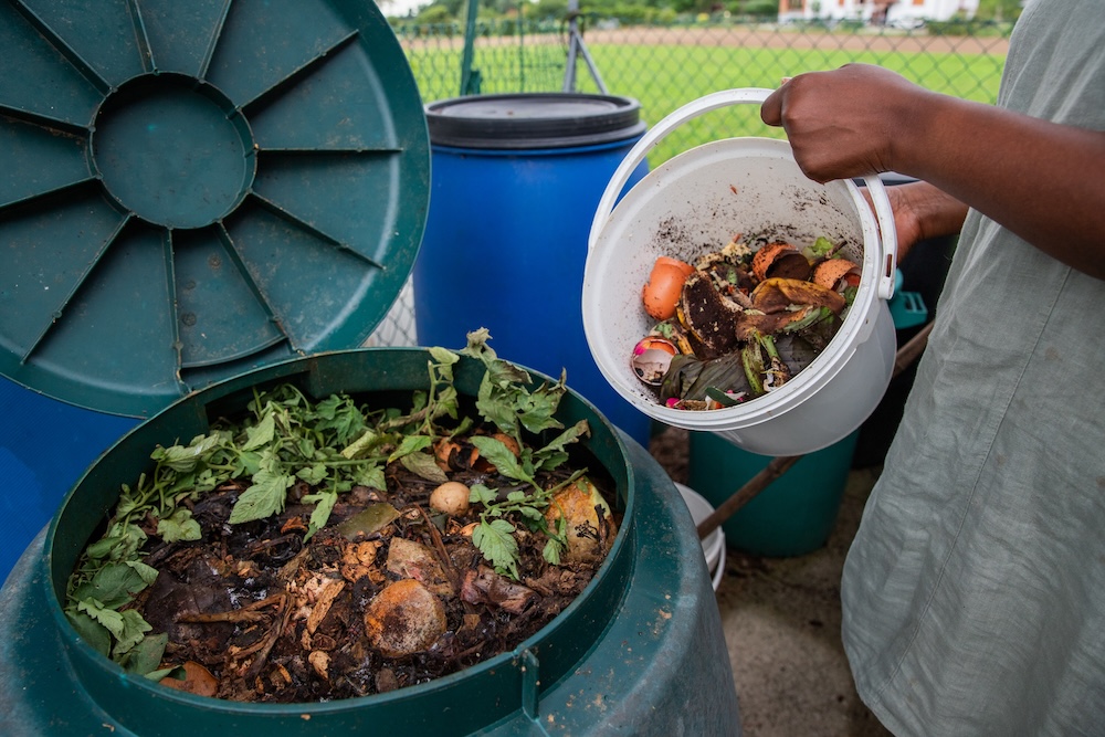 someone composting with plastic compost bin and plastic bucket
