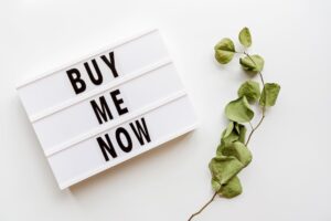 sign that says Buy Me Now with a green vine next to it