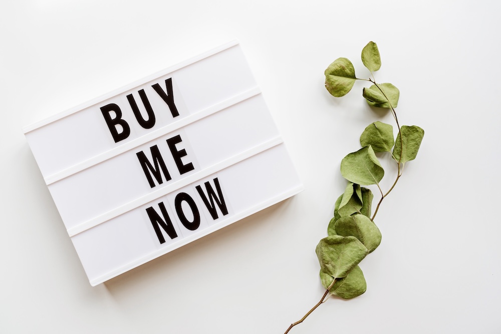 sign that says Buy Me Now with a green vine next to it
