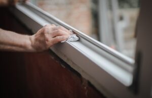 person wiping down window frame