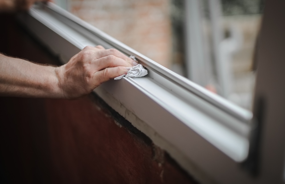 person wiping down window frame