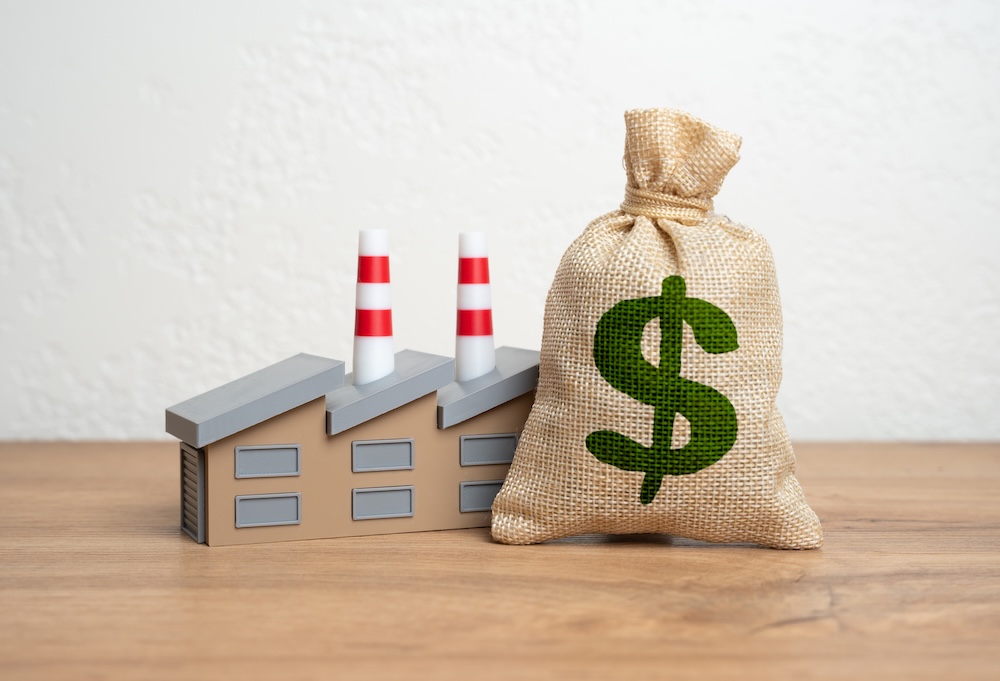 money bag sitting next to an industrial plant model
