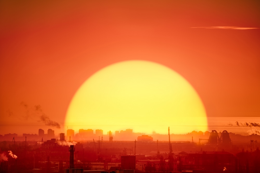 huge sun rising in the background of industrial landscape