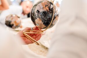 hands holding a small globe with golden stand