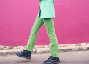 woman walking in green jeans black shoes and green blazer