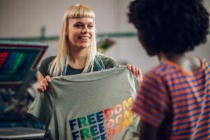 woman holding a shirt that says freedom in multicolors