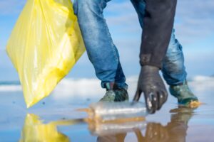 person cleaning up plastic from the ocean shore