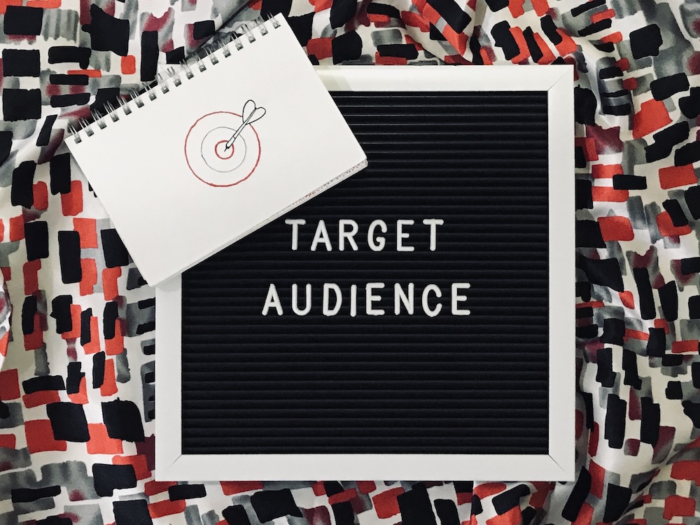 notebook with target and arrow sitting on a board that says target audience