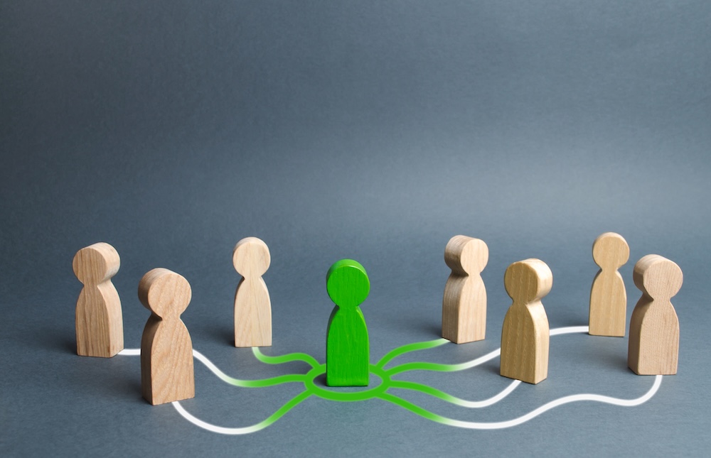 green wooden man in the center with green color moving towards other wooden men