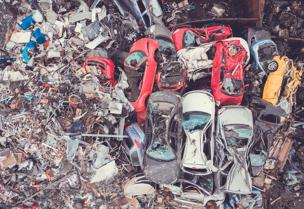 garbage in junk yard with vehicles piled