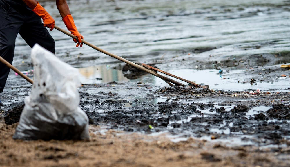 person using a rake to clean up trash on ocean shore