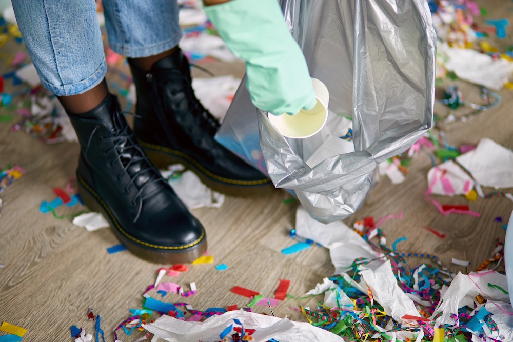 Person cleaning up trash from floor after a party