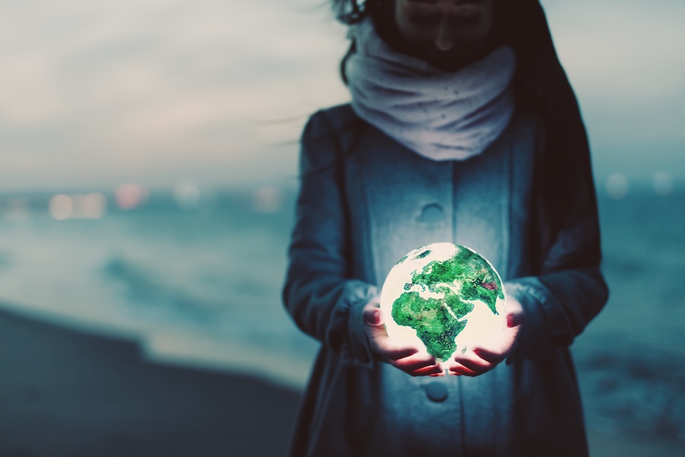 Woman holding an earth globe in her hands that is glowing