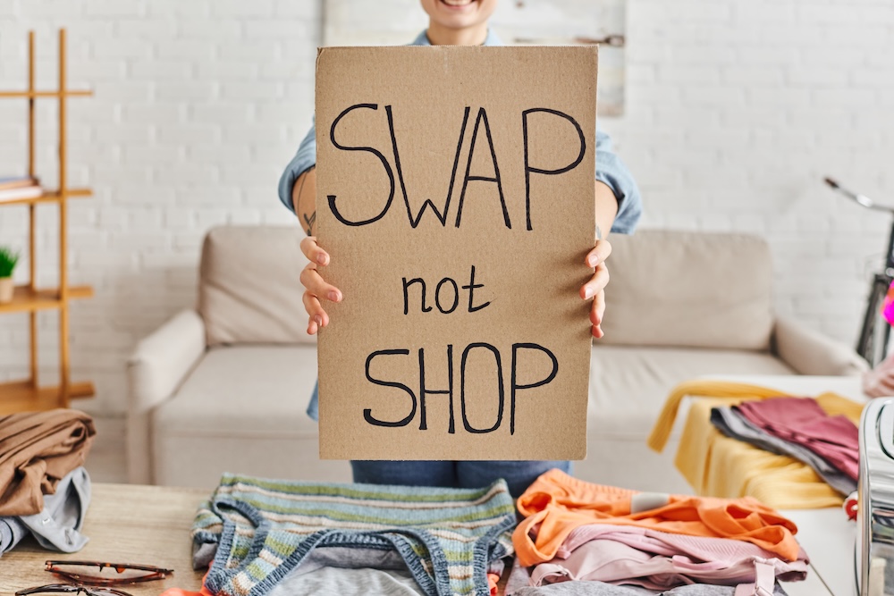 Young person holding a sign that says swap don't shop