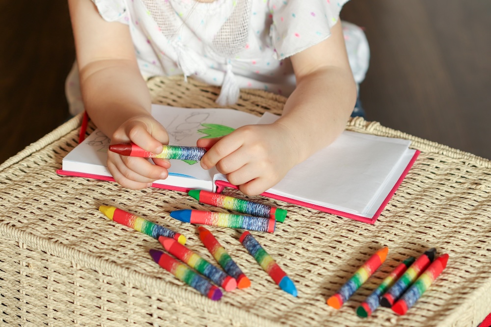 Young child drawing with wax crayons