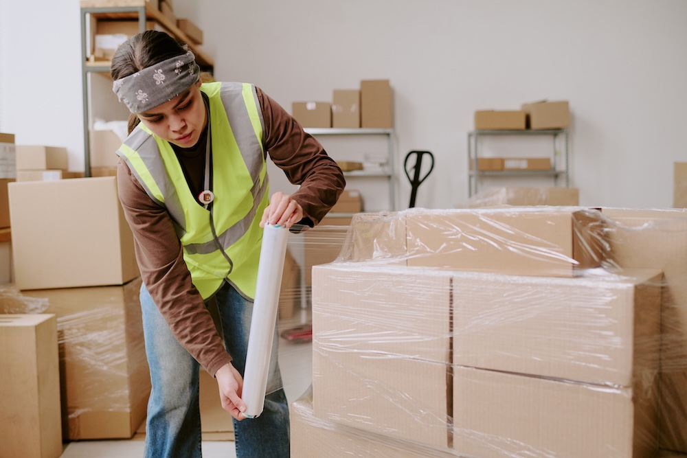 Woman wrapping moving boxes with shrink wrap