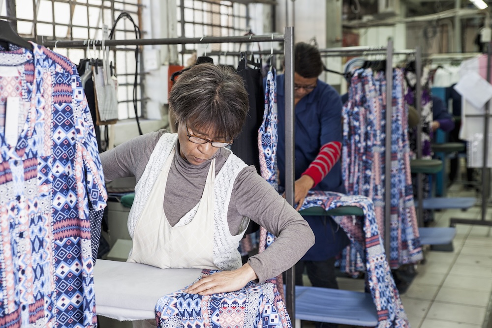 woman working in a garment factory ironing a dress