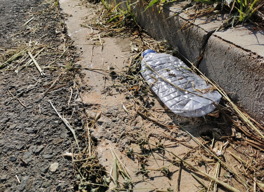 plastic bottle laying in a street gutter