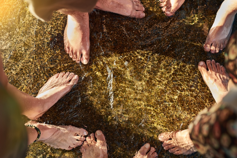 People standing in shallow water with feet making small ripples