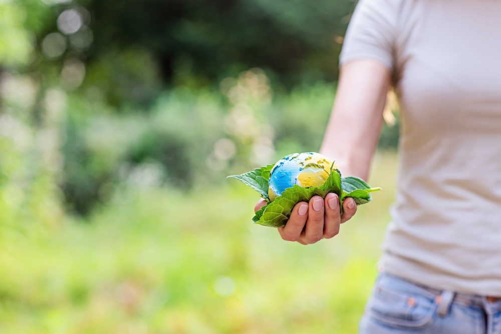 Young person holding a small globe and leaves in her hand