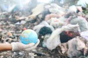 Hand holding a globe in a landfill