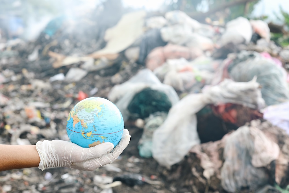Hand holding a globe in a landfill